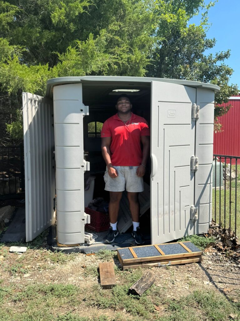 Junk Quest team member inside a backyard shed during a shed cleanout and junk removal project — local experts serving North Texas homeowners.