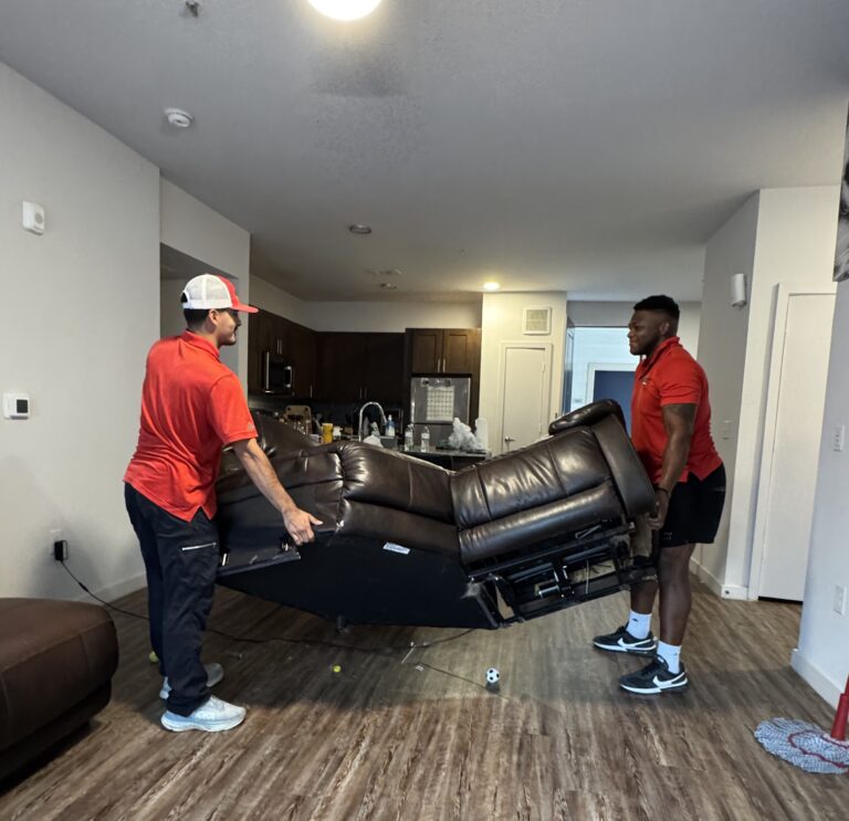 Junk Quest team lifting a heavy leather couch during a professional furniture removal service — safe, efficient, and reliable junk removal for local homeowners.
