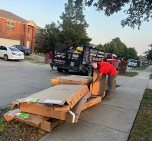Junk Quest crew loading flattened cardboard and reusable materials into a trailer during an eco-friendly junk removal and upcycling service in North Texas.