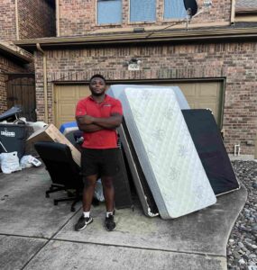 Junk Quest team member standing beside removed furniture and debris after a hoarder cleanout service in McKinney, TX — professional junk removal and property cleanup experts.