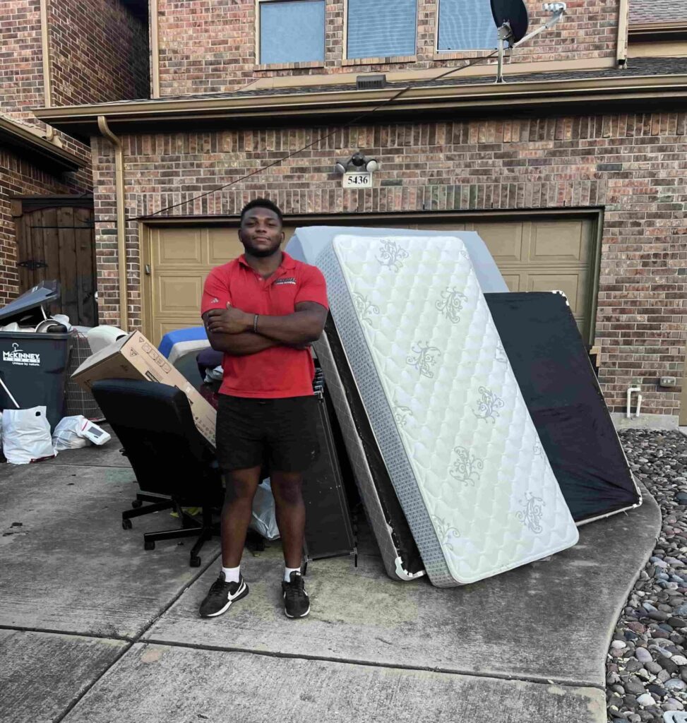 Junk Quest team member standing beside removed furniture and debris after a hoarder cleanout service in McKinney, TX — professional junk removal and property cleanup experts.