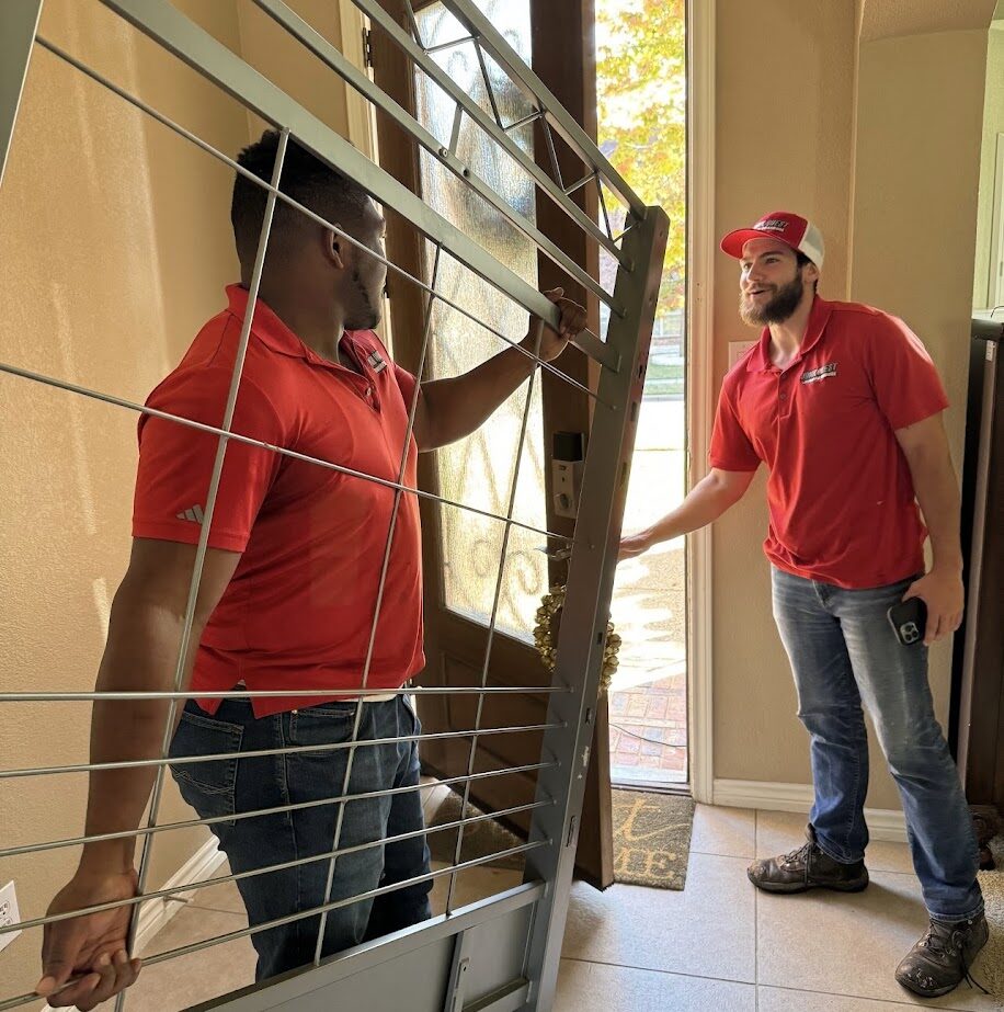 Junk Quest team removing a large door during a junk removal service in McKinney, TX, professional and friendly crew providing efficient home cleanout assistance.