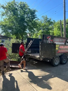 Junk Quest Removal crew safely loading construction waste into a trailer during North Dallas construction debris removal