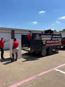 Junk Quest Removal crew loading debris and equipment into a commercial trailer during a warehouse cleanout in North Dallas