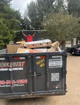 Junk Quest Removal crew loading office furniture boxes and debris into a commercial dumpster during an office cleanout in North Dallas
