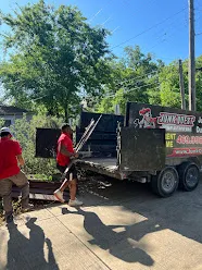 Junk Quest Removal crew loading tree branches and yard debris into trailer during yard waste removal service in North Dallas