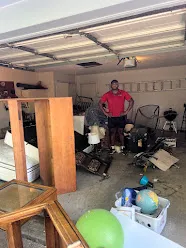 Junk Quest Removal team member standing in cluttered garage during cleanout in North Dallas