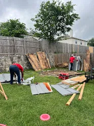 Junk Quest Removal crew clearing yard debris and construction wood panels during yard waste removal service in North Dallas backyard
