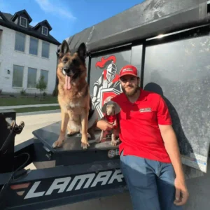 Jonathan from Junk Quest posing beside the company’s dump trailer with Hazel the German Shepherd and Henry the Weimaraner, the unofficial mascots of the local McKinney junk removal company.