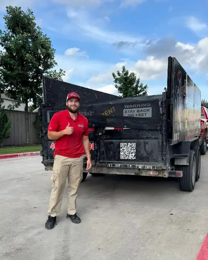 Junk Quest team member standing beside the company trailer after completing a garage cleanout in Anna, TX.