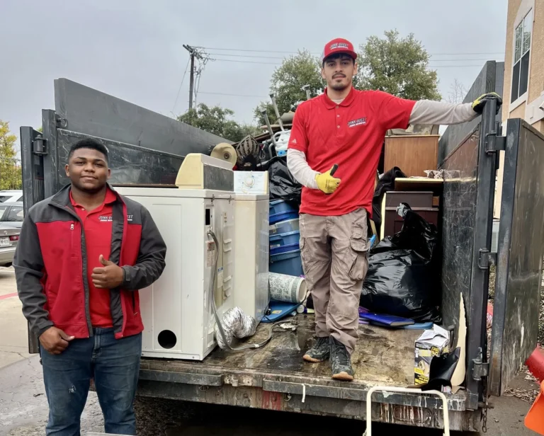 Junk Quest crew loading bulky appliances and debris into a trailer during a professional junk removal service
