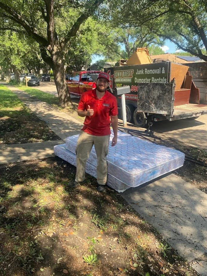 Junk Quest crew member giving a thumbs-up next to a mattress ready for curbside pickup in Dallas