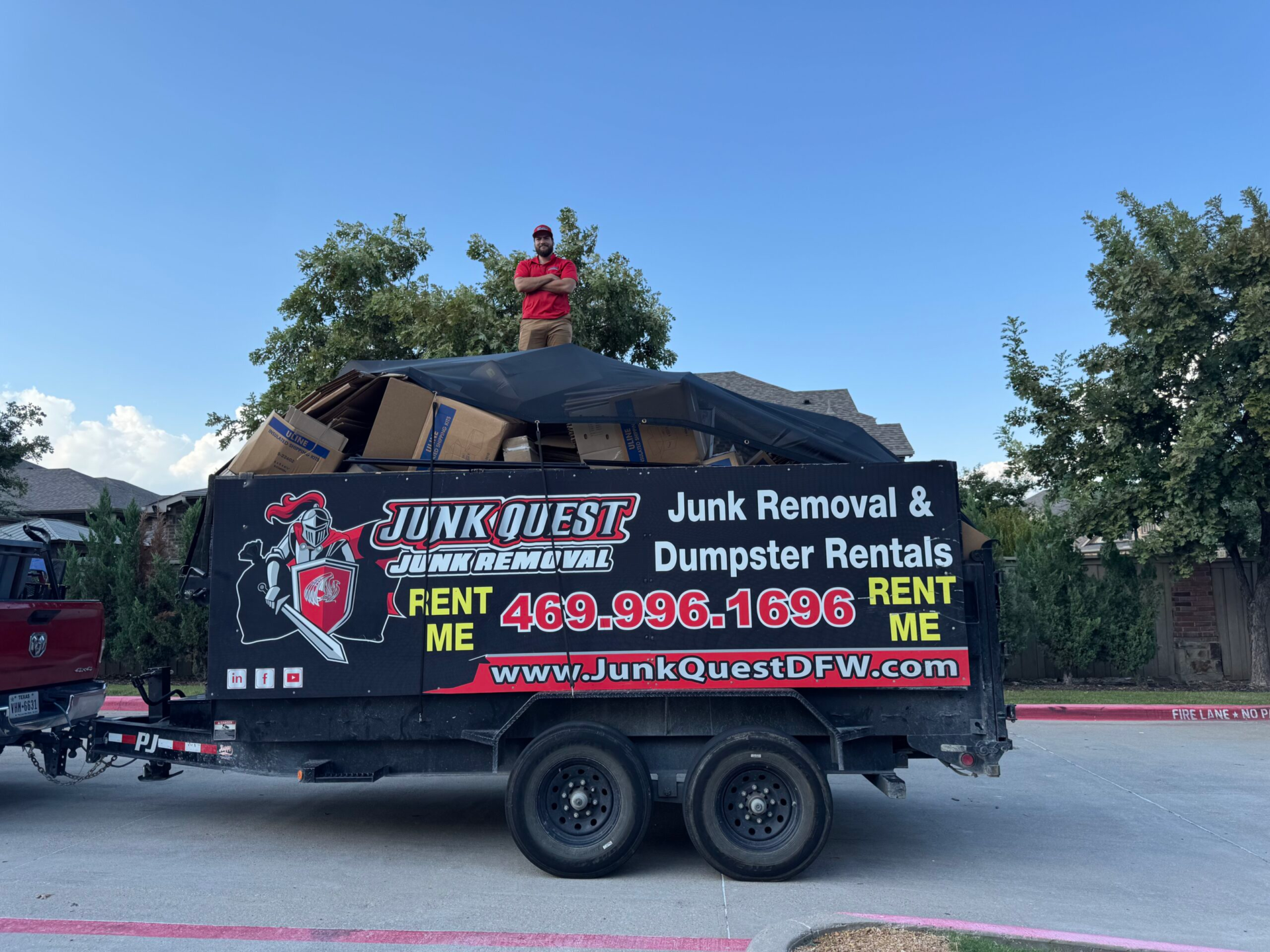 Junk Quest crew member atop a fully loaded trailer during a dumpster rental job