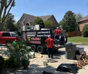 Junk Quest crew loading furniture and appliances onto their trailer during a junk removal job